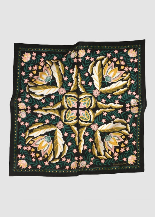 Decorative scarf with multicolor floral pattern with a black background laying on white surface