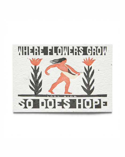 A postcard with letterpress text and illustration, featuring a figure sowing seeds among flowers, with the text 'WHERE FLOWERS GROW SO DOES HOPE - LADY BIRD'.