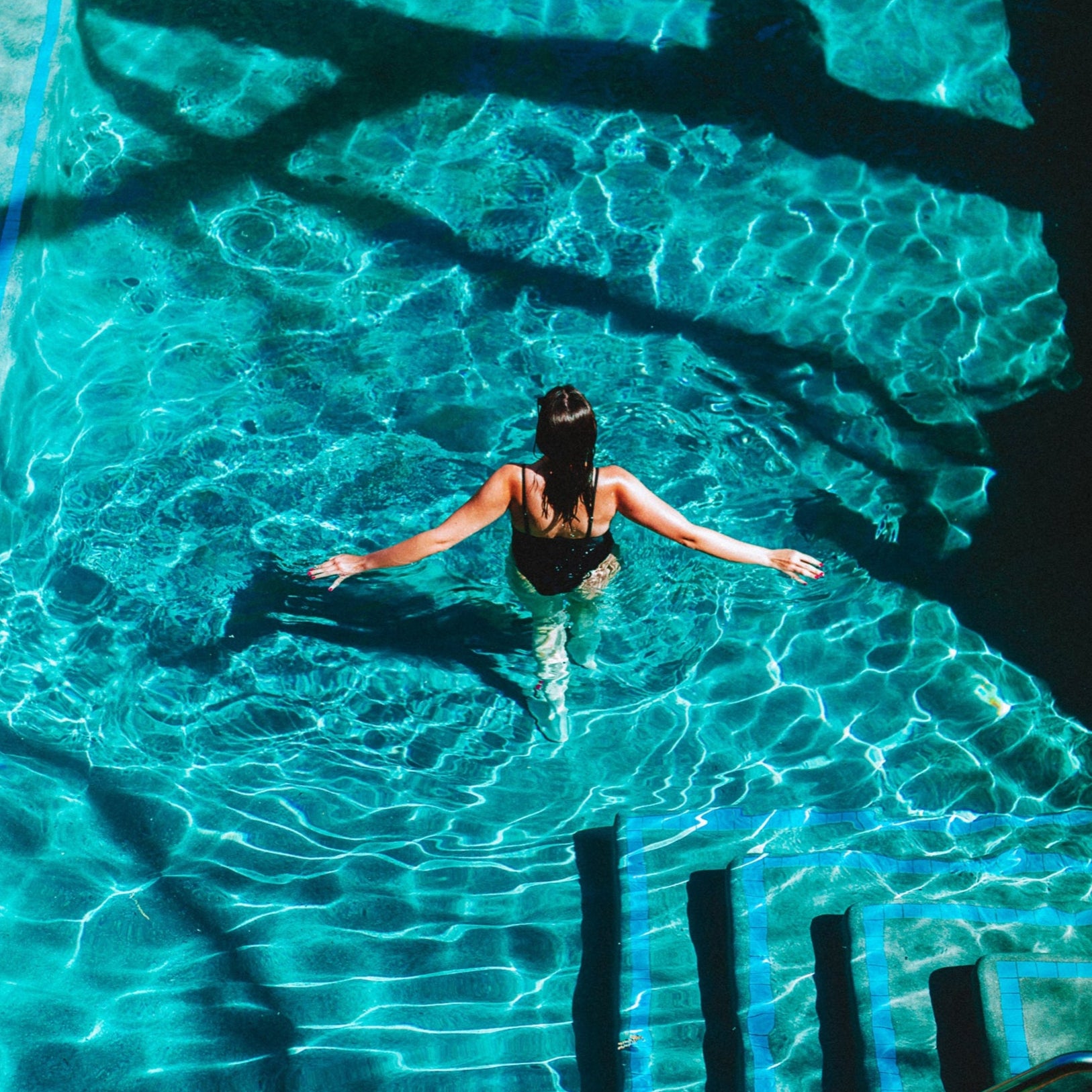 A person swimming in a pool with clear blue water.